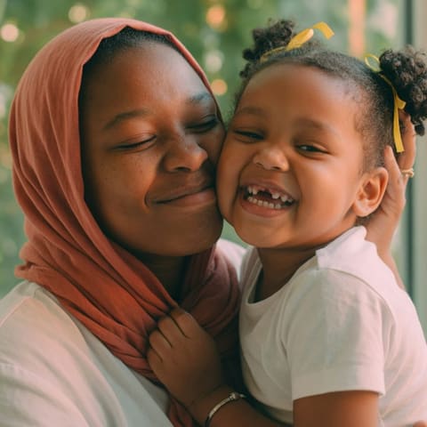 A warm close portrait of a parent and young child cheek to cheek outdoors